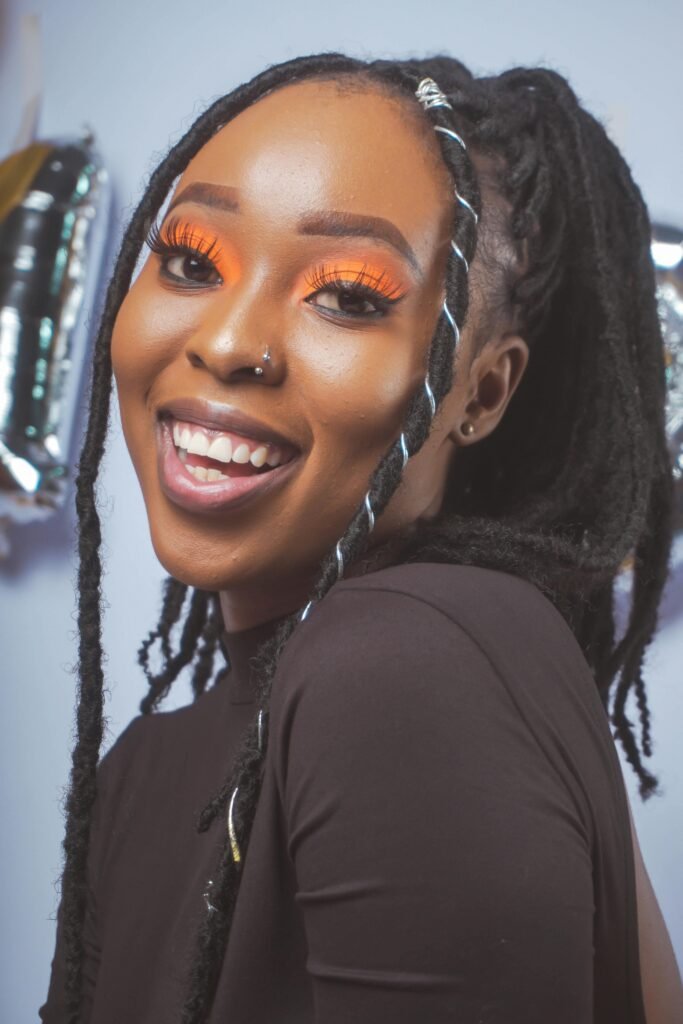 mulher preta linda sorrindo maquiada cabelos em trancas afro pearcing no nariz blusinha preta