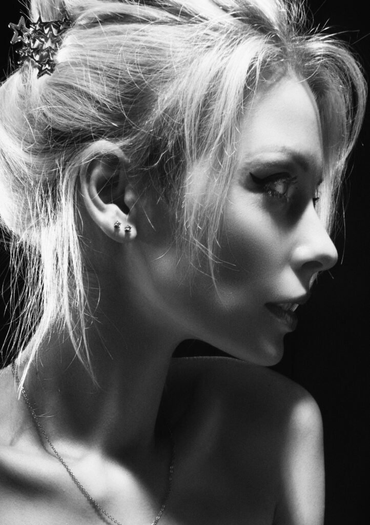foto em preto e branco de uma mulher com penteado cabelo preso com mexas soltas e dois pequenos brincos