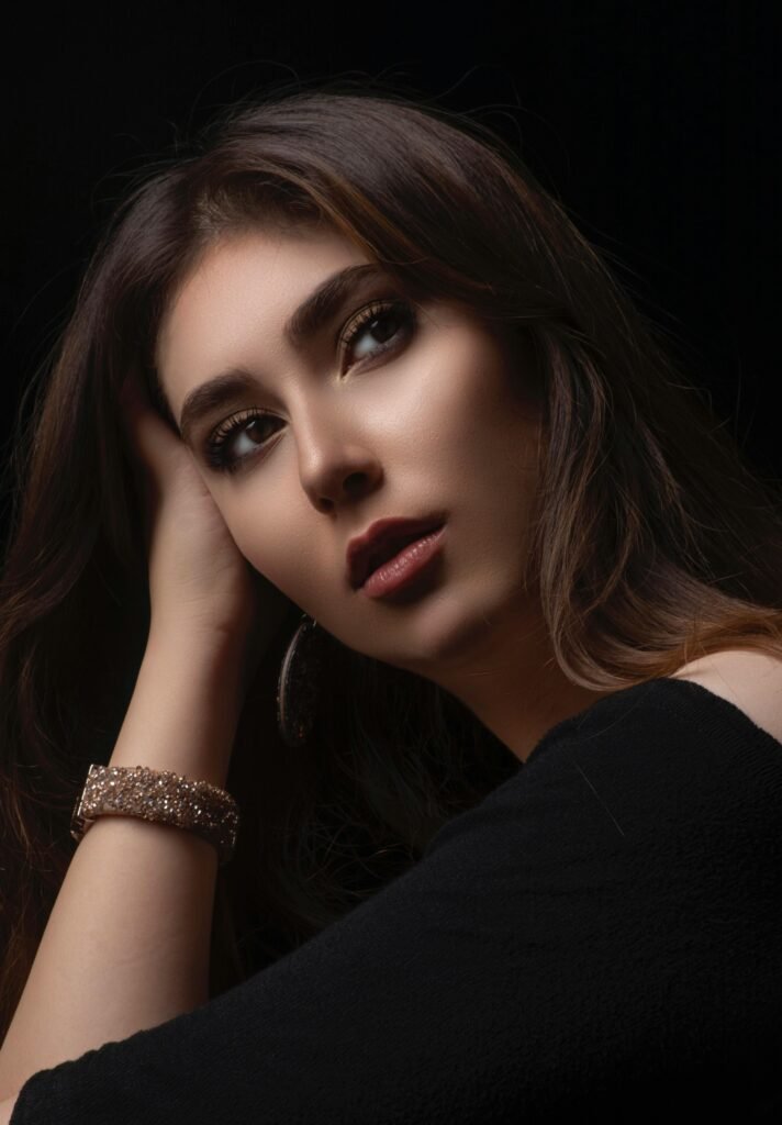 foto de mulher morena maquiada cabelos lisos longos olhos castanhos claros brinco redondo uma das mãos na cabeça