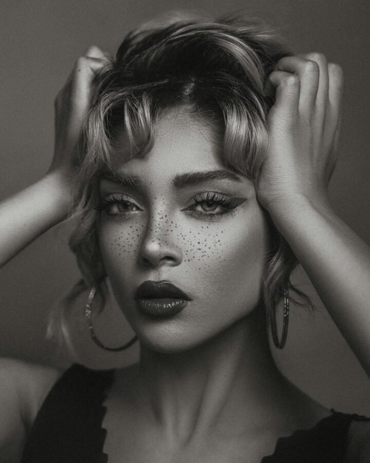 imagem de uma mulher em preto e branco brincos argolas grandes batom preto duas mãos segurando os cabelos foto de Pegah Sharifi pexels.com