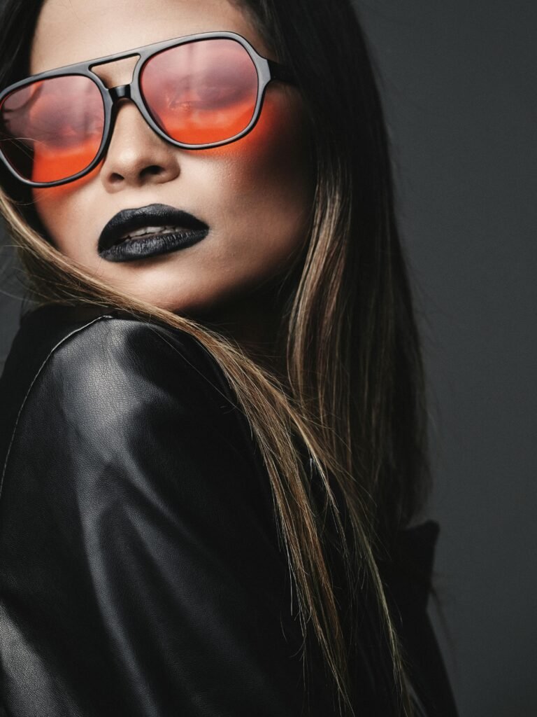 mulher cabelos lisos loiros oculos grande estiloso lentes laranja batom preto jaqueta preta