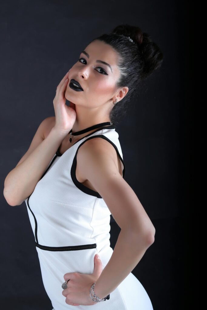 mulher branca linda maquiada cabelos lisos pretos presos brincos pequenos batom preto vestido social branco e preto