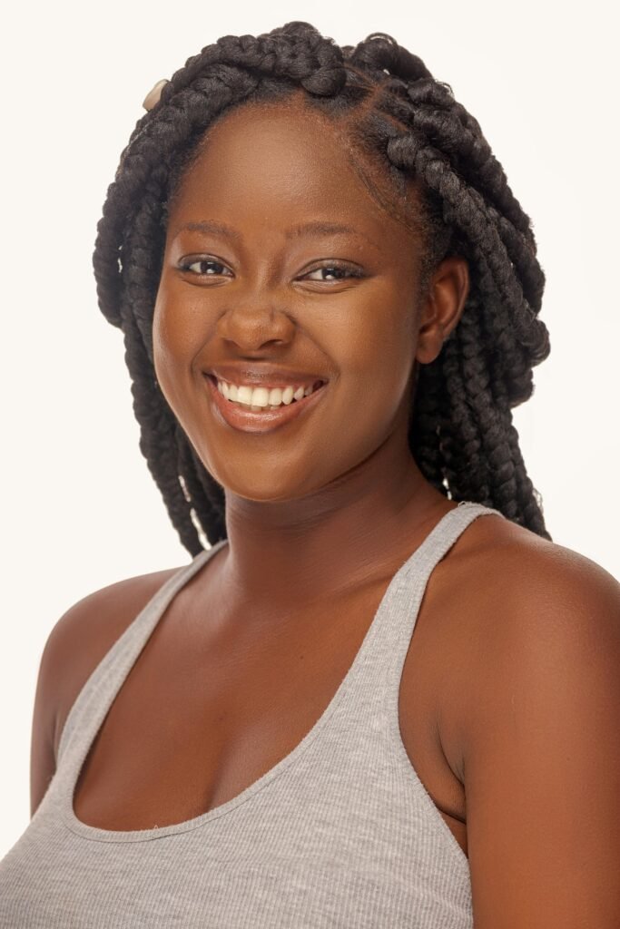 mulher sorrindo com cabelos longos pretos e varias trancas francesas camisetinha cinza