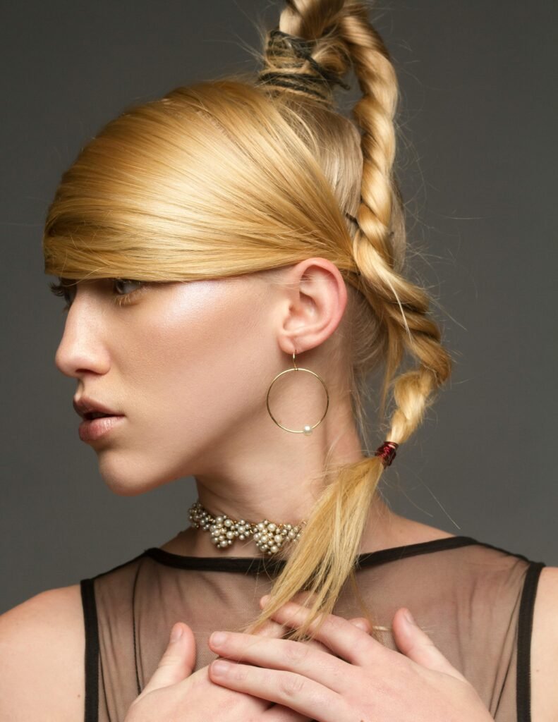 mulher loira com penteado estiloso cabelo preso com tranca brinco argola grande colar de perolas women’s hairstyles, penteados femininos estilo saúde e significado