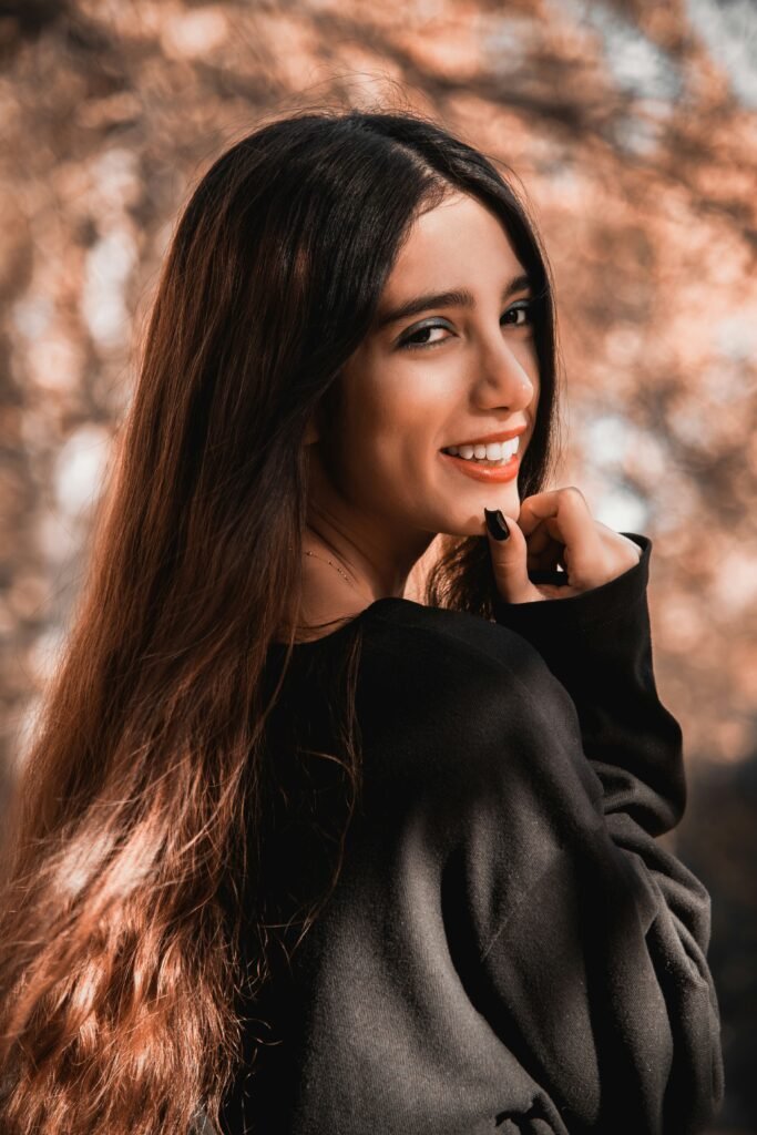 mulher sorrindo maquiada cabelos longos lisos uma das mãos no queixo blusa preta unhas cor preta night hair routine como a rotina do meu cabelo à noite pode transformar sua beleza
