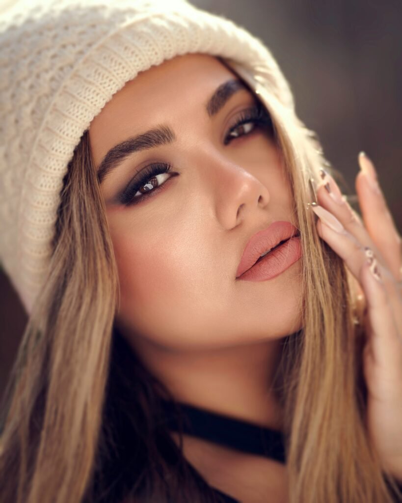 mulher maquiada batom nude olhos castanhos touca bege estilosa blusinha preta