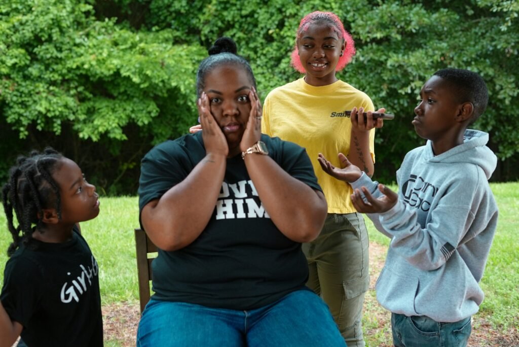 mãe com as mãos no rosto brincando com suas duas filhas pequenas e seu filho pequeno foto legal