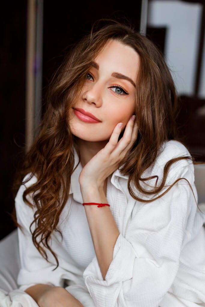 mulher maquiada leve sorriso olhos verdes e batom vermelho cabelos longos lisos uma das mãos no queixo o universo de beleza empoderamento e solução para mulheres com franciny ehlke fran by franciny ehlke