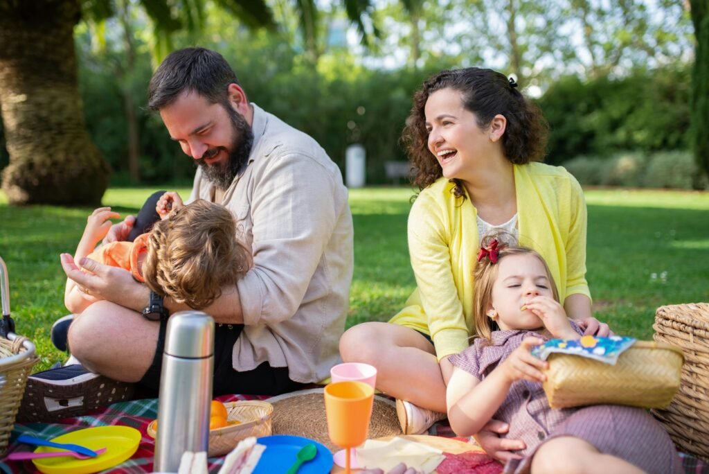 família no parque fazendo piquenique pai e mãe sorrindo celebrar com propósito o children’s day dia das crianças