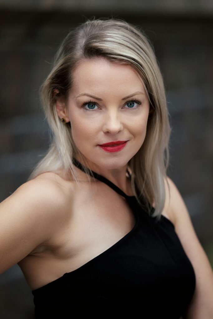 mulher maquiada loira olhos azuis batom vermelho blusinha preta kiss stick e bastão de beijo o segredo dos lábios poderosos em 2026 tendências dicas e segredos que ninguém conta