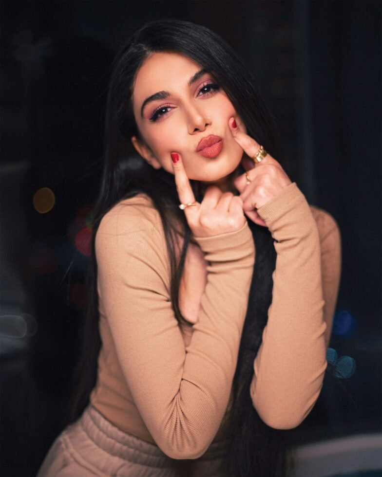 mulher maquiada cabelos lisos longos pretos dois dedos na boca fazendo biquinho batom vermelho foto de Ramin Azami unsplash.com