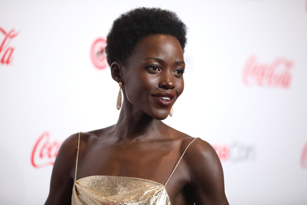 atriz lupita nyongo leve sorriso vestido social estiloso com alca brincos lindos no tapete vermelho creative commons