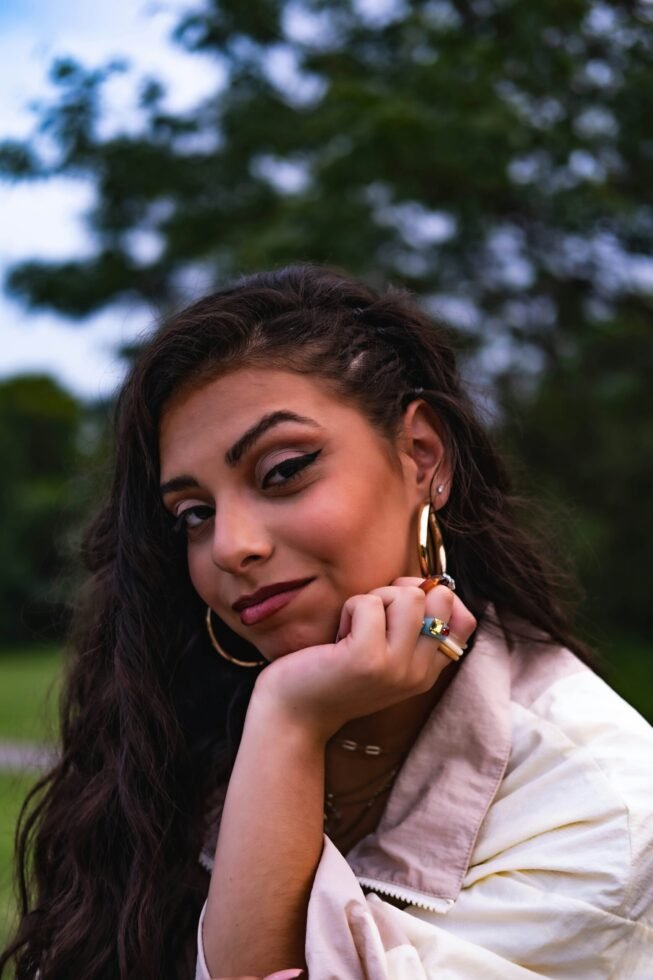 mulher maquiada leve sorriso cabelos longos lisos pretos brincos argolas grandes uma das maos no queixo foto de Cord Allman unsplash.com