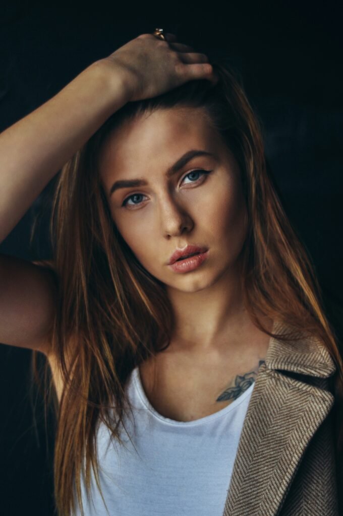 mulher maquiada olhos azuis cabelos lisos longos loiros blusinha branca tatuagem de flor no peito o segredo global do cat eye a evolução os misterios e a reinvencao do delineado de gatinha pelo planeta